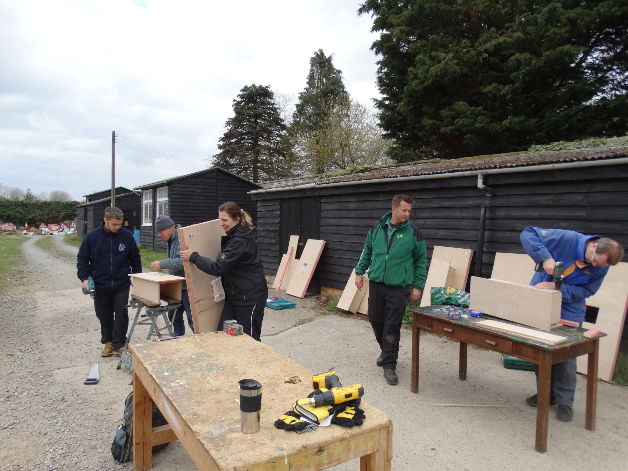 A photo from the FoTF Conservation Event - April 2019 - Mink Raft Construction at Santon Downham Workshops : Volunteers works outside on benches assembling components for mink rafts