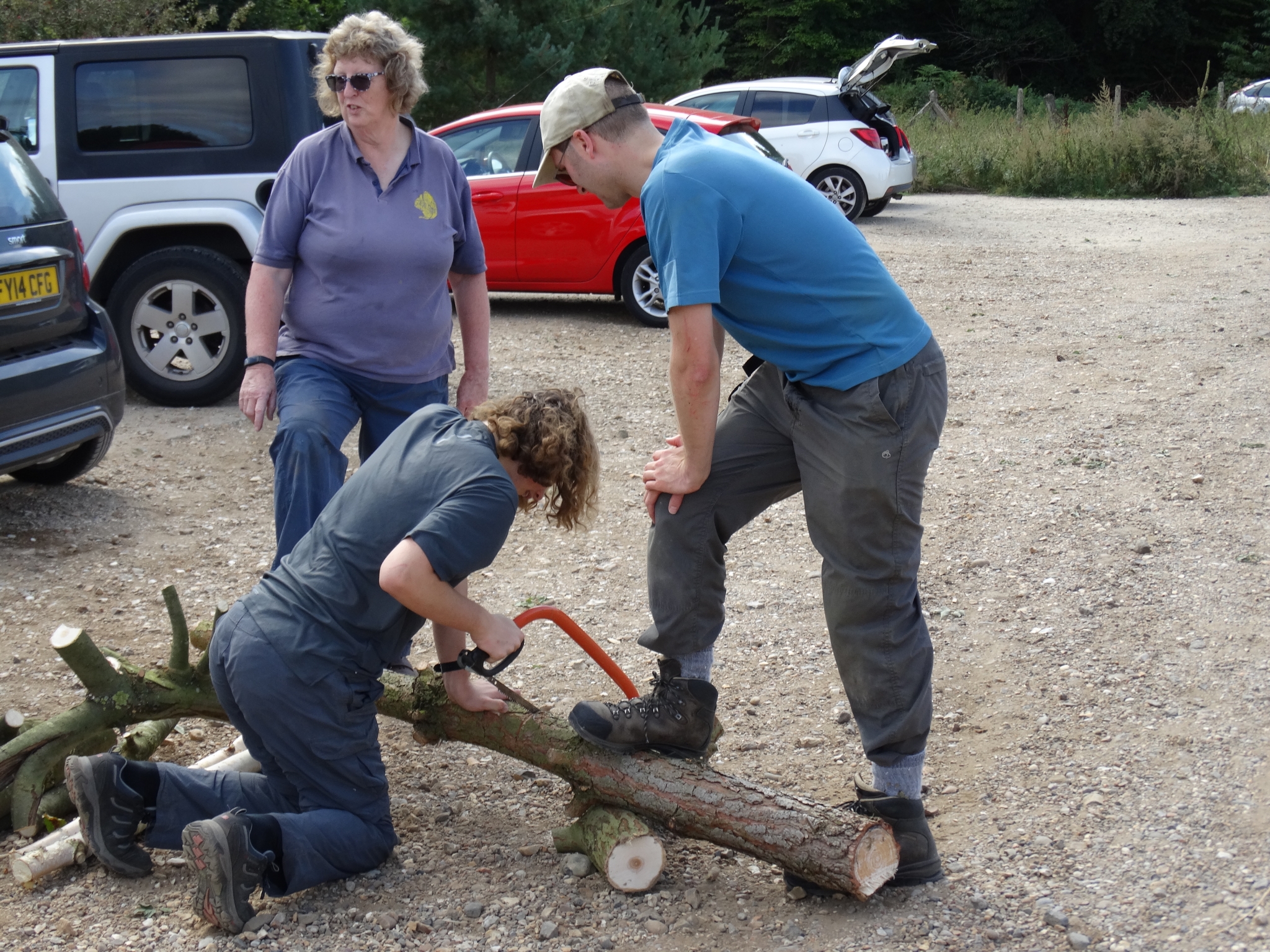 A photo from the FoTF Conservation Event - September 2019 - Scrub Clearance at Cranwich Camp : A volunteer saws a large log, while two other volunteer hold the log steady with their feet